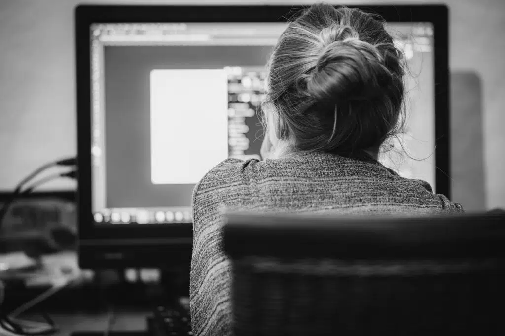 Black and white image of woman looking at computer screen in home office