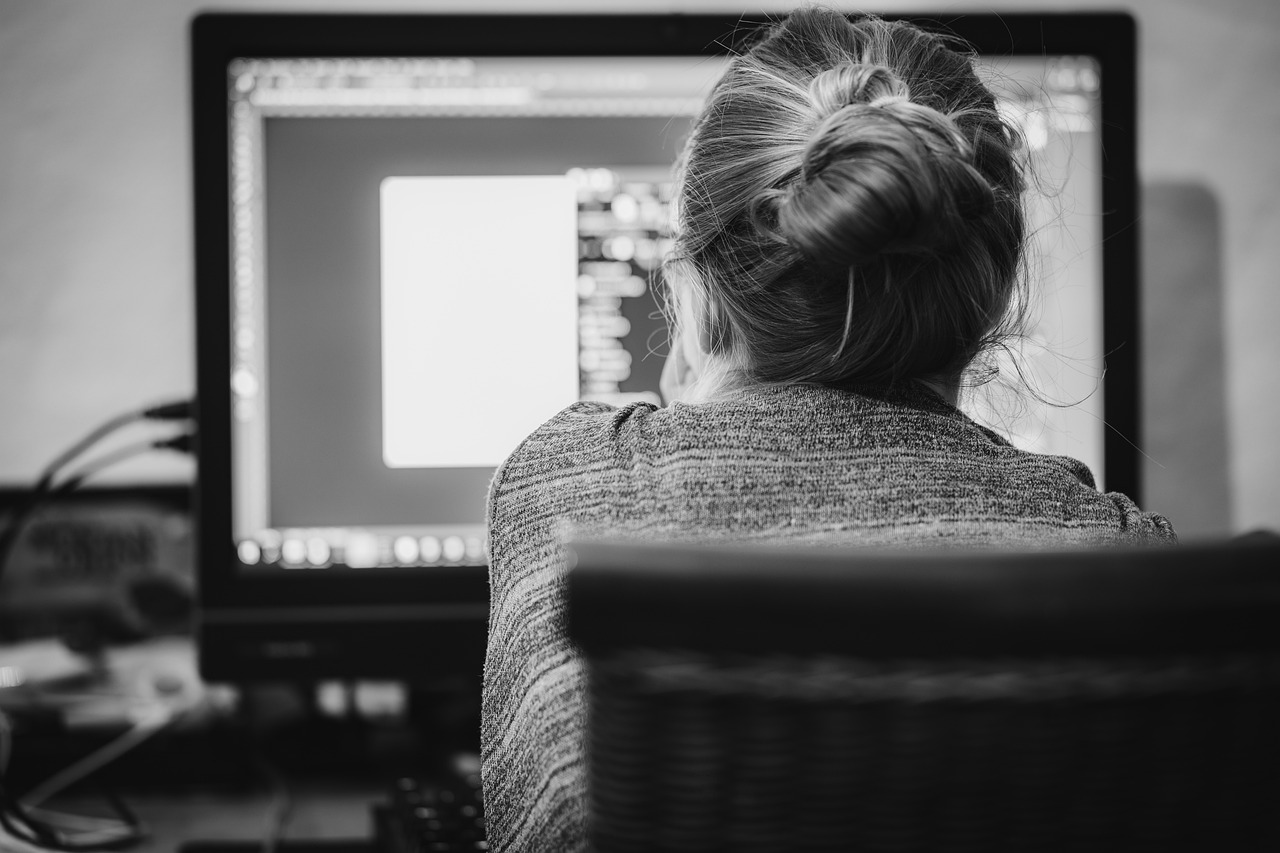 Black and white image of woman looking at computer screen in home office